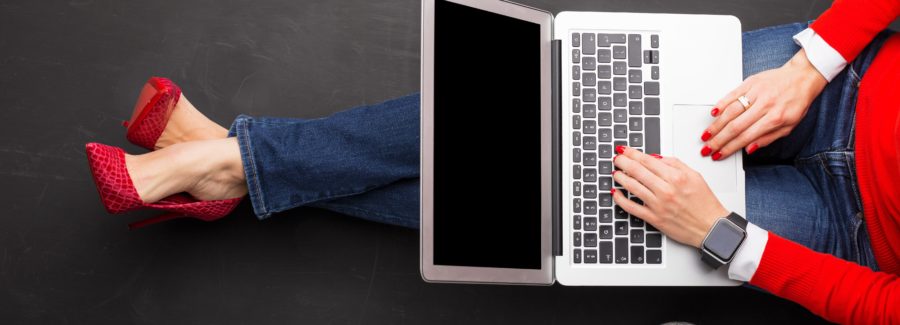 Woman sitting on ground at the office with computer in her lap